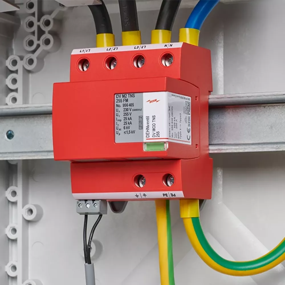 Red surge arrester, wired and mounted on a DIN rail in the switchgear cabinet.